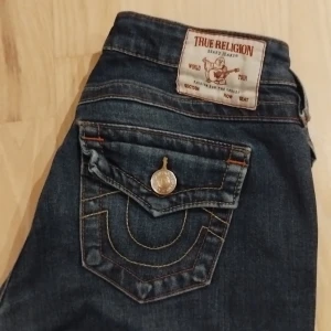 True Religion Joey Low Rise Flare köp/byta -  HÖR GÄRNA AV ER VID INTRESSE!! Svarar oftast väldigt snabbt ❤️❤️❤️Snygga mörkblå jeans från True Religion, modell Joey Low Rise Flare. Ser lite vintage ut. De har låg midja, utsvängda ben och ikoniska bakfickor med lock och dekorativa sömmar. I storlek w25!💕 I modellen Joey, Har en liten defekt längst ner (kan skicka bild bara fråga) Går och att byta mot samma märke!! 🤗