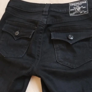 Svarta bootcut jeans från True Religion - Läs❤️!! Svarta jeans från True Religion med bootcut passform. Har haft cirka 2 gånger, har kvar prislappen, och är typ helt ny men har klippt bort lappen.💕 Säljer pågrund av att jag behöver pengar. Inget är trasigt över huvud taget, skicka dm ifall du är intresserad 💕