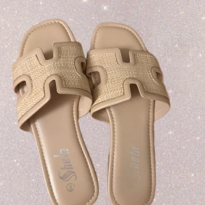Beige sandaler från Shein - Snygga beige sandaler från Shein med flätad ovandel och öppet tåparti. De har en fyrkantig form och bred rem med dekorativt mönster. Perfekta för varma dagar och enkla att glida i. Materialet är syntet och textil.