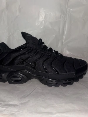 äljer svarta Nike TN (Air Max Plus) – nyskick -   Ett par stilrena svarta Nike TN i absolut nyskick. Skorna är helt oanvända och levereras med originalkartong, precis som vid köp i butik.  ✔ Oanvända – aldrig använda utomhus ✔ Originalkartong medföljer ✔ Klassisk svart färg som passar till allt  Perfekt för dig som vill ha ett par fräscha TN till ett bättre pris än nypris. Kan skickas eller mötas upp enligt överenskommelse.  Skriv vid frågor eller seriöst intresse!