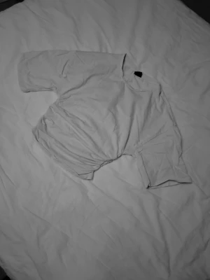 Vit croppad t-shirt från Gina Tricot - Säljer en vit t-shirt från Gina Tricot i storlek XS.💕 T-shirten har medel långa ärmar och en snygg croppad passform med cool snörningsdetalj på sidan. Materialet är mjuk bomull som känns skönt mot huden. Perfekt för dig som gillar stilrena och trendiga plagg.💕