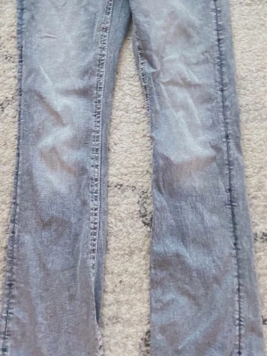 Grå bootcut jeans - Säljer ett par grå jeans med bootcut-snitt. Jeansen har en klassisk femficksdesign och är tillverkade i ett slitstarkt jeansmaterial. Färgen är en snygg, lite tvättad grå ton som passar till många olika stilar. Perfekt för dig som gillar retrovibbar och vill ha ett par jeans med lite extra attityd. Säljer Pga att de är för korta 