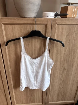 Vit spetskantad linnetopp - Säljer en vit linnetopp från 157 i storlek M. Toppen har tunna axelband och har spets detaljer