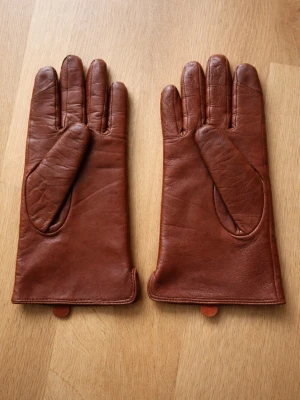 Bruna skinnhandskar från KappAhl. Strl. M - Snygga bruna skinnhandskar från KappAhl i storlek M. Handskarna har en klassisk design med mjukt foder på insidan och diskreta sömmar. Perfekt accessoar för kyliga dagar och passar till både jacka och kappa.