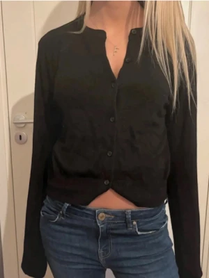 Svart kofta med knappar - Säljer en svart  kofta med långa ärmar och knappar framtill. 