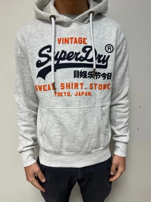 SuperDry Hoodie  - Säljer en riktigt snygg och skön hoodie från SuperDry! Den är i storlek S men passar även M. Modellen på bilden är 184cm och väger 75kg. 