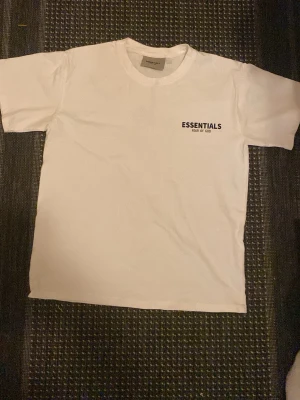 Essentials Fear of God t-shirt - Säljer en clean vit t-shirt från Essentials Fear of God. Klassisk passform med korta ärmar och rund hals. Diskret svart logga på bröstet. Extremt billig och nästan ny. FRAKTAS SAMMA DAG!👍