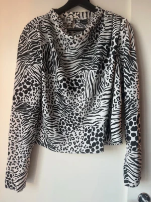 Zebramönstrad långärmad topp Gina Tricot  - Säljer en svartvit långärmad topp från Gina Tricot  med coolt zebramönster och leoparddetaljer. Toppen har en lös passform och mjukt material som känns skönt mot huden. Perfekt för dig som vill sticka ut med ett djurmönstrat plagg.