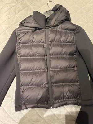 Svart pufferjacka från Zara med huva - Säljer en svart pufferjacka från Zara i storlek S. Jackan har huva, dragkedja framtill och quiltad design på både fram- och baksida. Ärmarna är släta och materialet är en mix av polyester och syntet. Perfekt för kyliga dagar och riktigt snygg till streetwear.