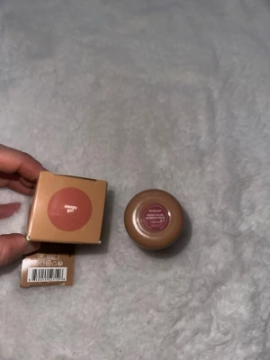 Rhode Pocket Blush Sleepy Girl - Rhode Pocket Blush i färgen Sleepy Girl är ett krämrouge i stickformat med en mjuk rosa ton. Förpackningen är beige och kompakt, perfekt att ha med sig i väskan. Enkel att applicera direkt på kinderna för en fräsch och naturlig look.