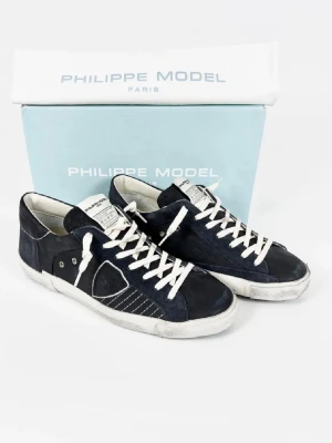 Philippe Model blå sneakers - Snygga Philippe Model sneakers i mörkblå mocka med vita snören och detaljer. Skorna har en rund tå och platt sula med tydlig logga under. Perfekt för dig som gillar stilrena och coola sneakers med fransk design.