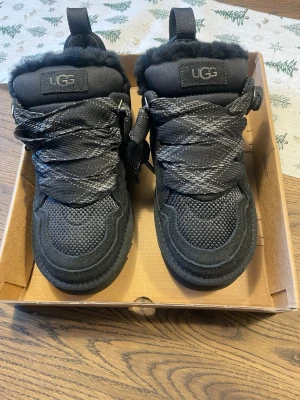 Svarta UGG boots - Säljer ett par svarta snygga UGG boots med grov platt sula och snörning. Skorna har ett fluffigt pälsfoder på insidan och detaljer i mocka och syntet på utsidan. Säljer då jag köpte en storlek för liten, aldrig använda. Det är bara att skriva om du har frågor 💗☺️nypris: 2499kr