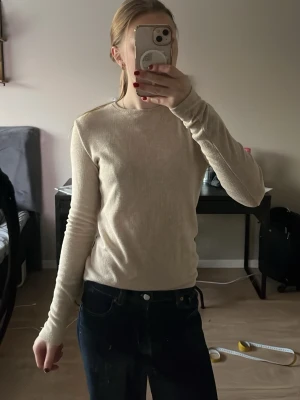 Beige ribbad långärmad tröja - En stilren beige långärmad tröja med ribbad struktur och rund halsringning. Perfekt att bära till jeans eller kjol för en enkel och clean look. Materialet känns mjukt, stretchigt och lätt mot huden. Skickar plagget så fort som möjligt!