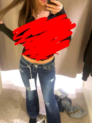 Blå bootcut jeans med slitningar - Snygga blå jeans med bootcut-snitt och slitna detaljer på benen. Jeansen har låg midja och klassiska fickor fram och bak. De är tillverkade i jeansmaterial och har kontrastsömmar som ger en cool look. Perfekta för dig som gillar en avslappnad stil.