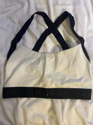 Tränig/simnings bh - Säljer en vit bh som både fungerar till simning och till gymmet, med svarta band och korsad rygg. Från sailracing. Aldrig använd