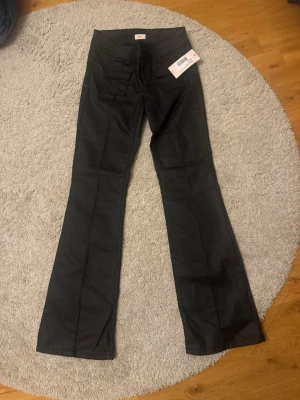 Svarta Lågmidjade bootcut jeans från Nelly - Snygga svarta bootcut jeans från Nelly med låg midja och fickor både fram och bak. Jeansen har en klassisk bootcut-passform som ger en schysst siluett och är tillverkade i ett mjukt jeansmaterial. Perfekta till sneakers eller boots.