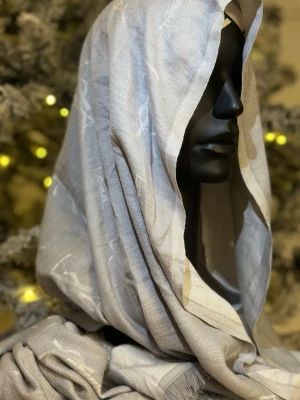 Grå YSL sjal med fransar - Snygg och lyxig grå sjal från Yves Saint Laurent med diskret logotypmönster och fransar längs kanterna. Perfekt att slänga över axlarna för en stilren look. Tunn och mjuk i materialet.