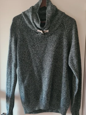Grå stickad tröja med snörning Livergy - Säljer en mörkgrå stickad tröja från Livergy i storlek L. Materialet är grovstickat och ger en mysig känsla, perfekt för kyliga dagar.