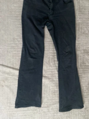 Svarta bootcut jeansbyxor i M - Svarta jeansbyxor i bootcut-modell med klassisk femficksdesign. Byxorna är tillverkade av en mix av bomull, polyester, viskos och elastan vilket gör dem både mjuka och stretchiga. Perfekt passform och snygg siluett med utsvängda ben.