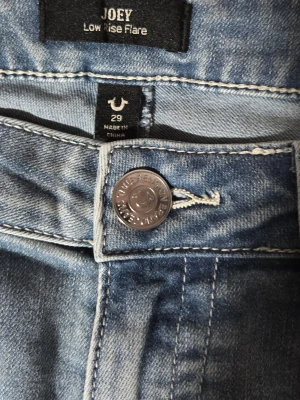 True Religion Joey Low Rise Flare jeans - Säljer ett par ljusblå True Religion Joey Low Rise Flare jeans, nya utan prislapp bara testade! Jeansen är lågmidjade och har lite lätt stretch i materialet! Skriv om du har några frågor eller är intreserad! Pris kan diskuteras! ( ny pris: 1300 )🫶😊                     Midjemått: 42 cm Från knapp - skrev: 21 Innebenslängden: 81 cm  Total längden: 105 cm 