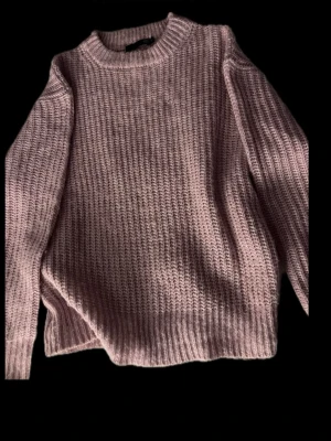 Ljusrosa stickad tröja Jasnoróżowy sweterek dzianinowy - Mysig ljusrosa stickad tröja från 157 med grov ribbstickning och rund hals. Tröjan har långa ärmar och en relaxed passform som gör den perfekt för kyliga dagar. Enkel och stilren design som är lätt att matcha med jeans eller kjol.