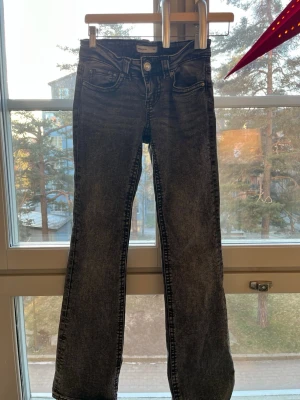 Bootcut jeans från Perfect Jeans lågmidjade, svart från Ginatricot - Bootcut jeans i svart tvättad denim från Perfect Jeans. Modellen har klassiska fem fickor, knappstängning och bälteshällor. Snygga detaljer med markerade sömmar och bakfickor med knapp. Jeansen är från Ginatricot i EU34 och är utsvängda. Använd ett fåtal gånger men är i väldigt gott skick utan några som helst skavanker. Jeansen är väldigt lågmidjade