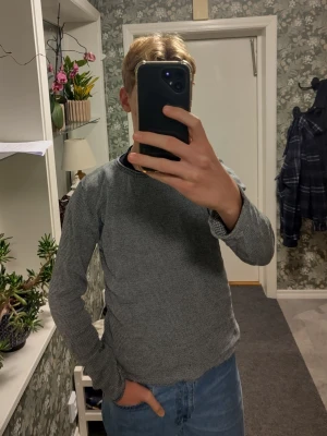 Grå långärmad tröja - Säljer en grå långärmad tröja från Minimum i 100% bomull. Tröjan har ett diskret randigt mönster och en rund hals. Passformen är normal och materialet är mjukt och skönt mot huden. Perfekt för dig som gillar enkel och stilren design.