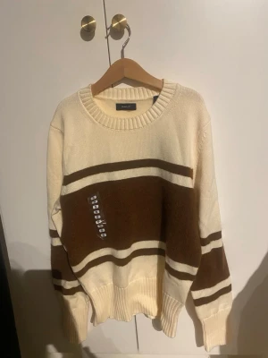 Randig stickad tröja från GANT - Säljer en  stickad tröja från GANT i beige och brunt med breda ränder. Tröjan har rund hals, ribbade muddar och lång ärm. Pris är går att diskutera
