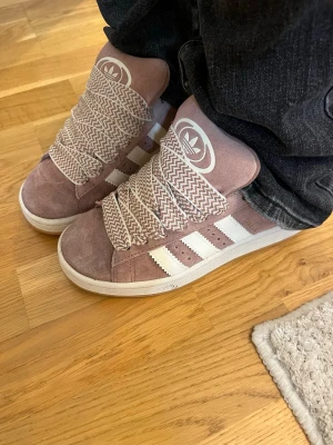 Adidas Campus sneakers rosa/vita - Ge gärna prisförslag❗️Säljer ett par jättefina Adidas Campus sneakers i en snygg ljusrosa färg med vita detaljer och klassiska tre ränder på sidan. Skorna har breda, randiga snören i vitt och rosa. Endast använda 4-5 gånger💖 säljer pågrund av att de inte kommer till användning