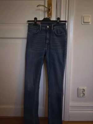 Acne Studios Blå Konst jeans blå - Säljer ett par klassiska blå jeans från Acne Studios Blå Konst. Jeansen har raka ben (skinny) och hög midja. Snygg mörkblå tvätt och diskreta detaljer. Perfekta till en chill och stilren look. Storlek 27/32.