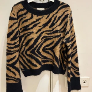  Ny Zebramönstrad stickad tröja H&M - Cool stickad tröja från H&M med zebramönster i svart och beige. Rund halsringning och långa ärmar. Mjuk och fluffig känsla, perfekt för att ge din outfit lite edge. Passar dig som gillar djurmönster och vill sticka ut.