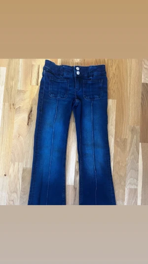 Mörkblå bootcut jeans med fickor - Säljer ett par snygga mörkblå lowwaist boutcut jeans med snygga fickor där fram. Jeansen är i storlek 164 och är nästan helt oanvända. Priset kan diskuteras vid snabbköp💕