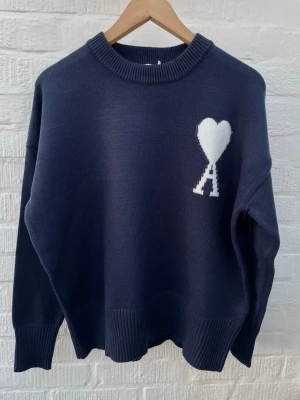 Ami Paris tröja  - Marinblå stickad tröja i storleken M ifrån Ami Paris i helt nytt skick med lappen på. Tröjan är av 100% bomull och har inga täcken på slitage eller fläckar. Har du frågor är det bara att skriva. 