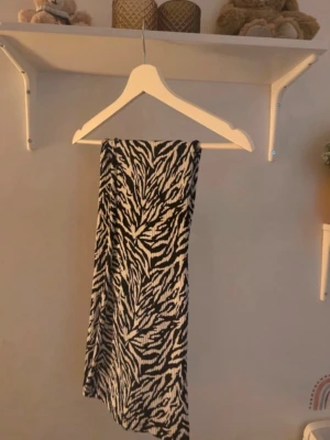 Svartvit zebramönstrad byxor  - Säljer en svartvit byxor med coolt zebramönster. Kjolen har en rak och flowy passform som ger en snygg siluett. Perfekt för dig som gillar att sticka ut med djurmönster. Materialet känns mjukt och följsamt mot huden.