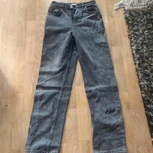 Grå raka jeans i vintage-stil - Snygga grå jeans med rak passform och klassisk femficksdesign. Jeansen har en hög midja och är tillverkade i ett slitstarkt denimtyg. Perfekta för dig som gillar en avslappnad och tidlös look.
