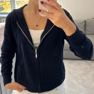 Mörkblå hoodie med dragkedja - Mörkblå hoodie med huva och hel dragkedja framtill. Tröjan har långa ärmar, ribbade muddar och är tillverkad i ett mjukt material.