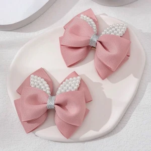 2st Rosa diadem med pärlor och rosett - Snyggt rosa diadem med stor rosett i ribbad textil och glittrigt silverband i mitten. Dekorerad med vita pärlor som ger en extra touch. Perfekt för att lyfta din look med lite glam och söt vibe.