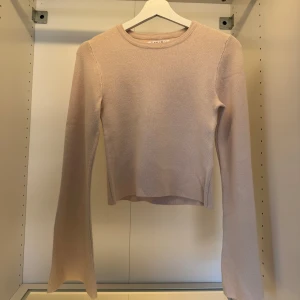 Beige stickad tröja med vida ärmar - Superfin beige stickad tröja från New Yorker med vida, långa ärmar och rund halsringning. Tröjan har en något croppad passform och är perfekt för lager-på-lager under hösten och vintern. Enkel och stilren design som passar till allt.