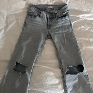 Bootcut jeans med slitna knän från Nelly - Superfina ljusblå jeans med rosa fickor från Nelly storlek 32. De är använda men inget som syns förutom nere på byxbenet då dom är lite söndertrampade men ingen som man tänker på. (sista bild) Tvättas innan de skickas!!