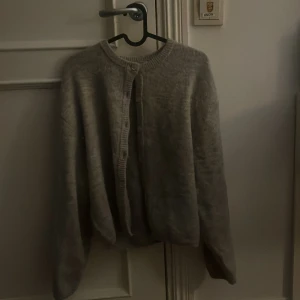 Grå kofta från Gina Tricot - Mysig grå kofta från Gina Tricot i stickad kvalitet. Rund halsringning, knäppning framtill med stora knappar och långa ärmar. 