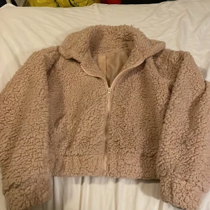 Aprikos  teddyjacka från SHEIN, S - Mysig aprikos teddyjacka från SHEIN i storlek S. Jackan har dragkedja framtill, hög krage och är fodrad med slätt tyg på insidan. Perfekt för kyliga dagar och ger en chill vibe till din outfit.