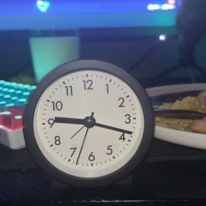 Svart rund väckarklocka från Blue Canyon - Säljer en stilren och enkel rund väckarklocka från Blue Canyon. Klockan har svart plastkropp, vit urtavla med svarta siffror och visare. Batteridriven med tydlig on/off-knapp på baksidan. Perfekt för skrivbordet eller nattduksbordet.