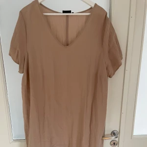 Beige långklänning från Zizzi - Säljer en beige långklänning från Zizzi i storlek M. Klänningen har v-ringad hals, korta ärmar och ett volangparti längst ner. Materialet är mjukt och lätt, perfekt för varma dagar. Enkel och stilren design som är lätt att matcha med accessoarer.