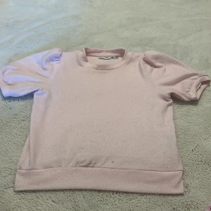 Ljusrosa kortärmad tröja 157 - Supersöt ljusrosa tröja från 157 med puffiga korta ärmar och rund hals. Mjuk och skön i bomullsmix, perfekt för vår och sommar. Enkel men ändå stylish, passar till jeans eller kjol för en chill look.