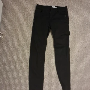 Svarta skinny jeans från 157, stl 160 - Svarta jeans från 157 i modellen Skippy. Byxorna har klassisk femficksdesign, smal passform och dragkedja med knapp. Perfekta för dig som gillar en enkel och stilren look. Materialet är mjukt och stretchigt för extra komfort.