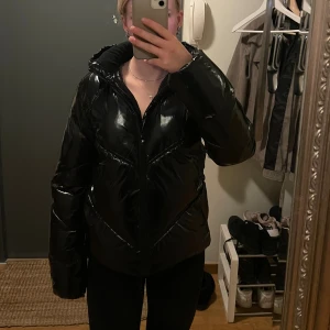 Calvin Klein vinterjacka - Säljer denna fina, glasiga och bekväma svarta vinterjackan från Calvin Klein med fina detaljer. Super skönt att ha på sig och håller värmen riktigt bra! Jackan har storlek 16, vilket motsvarar ungefär xs/s