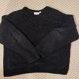 Svart stickad tröja från KappAhl - Mysig svart stickad tröja från KappAhl med rund halsringning och ribbade muddar vid ärmslut och nederkant. Perfekt för lager-på-lager och chill dagar. Klassisk modell som funkar till det mesta.