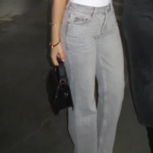 Gråa raka jeans med hög midja - Säljer ett par gråa jeans med hög midja och raka ben. Jeansen har klassisk femficksdesign och stängs med knapp och dragkedja. Perfekta för en chill och trendig look.