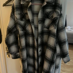 Rutig kappa med bälte🤍 - Säljer en lång och oversized höstkappa i svart, beiget och vitt. Jackan har klassisk krage, knappar framtill, två bröstfickor och ett matchande bälte i midjan. Materialet är mjukt och känns lite ulligt, perfekt för lager-på-lager och nu i höst🥰🍂