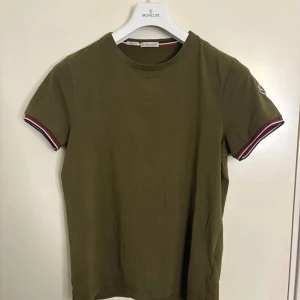 Moncler T-shirt  - Moncler T-shirt som sticker ut på sitt sätt men den sticker ändå ut. T-shirten är i en oliv grön färg, som passar till alla säsonger under åren. Självklart är den äkta!! Tveka inte med att skriva funderingar😁